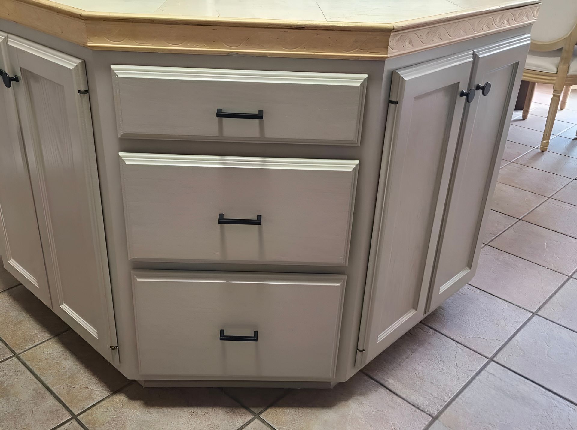 White kitchen island with drawers and cabinet doors on a tiled floor