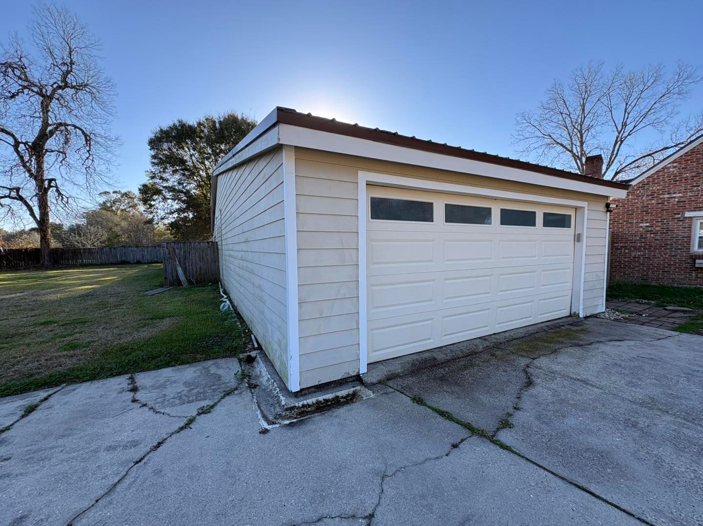 Detached white garage with a brown roof and concrete driveway in a residential yard