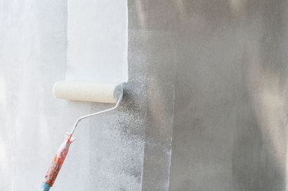 Paint roller coating a wall with white paint