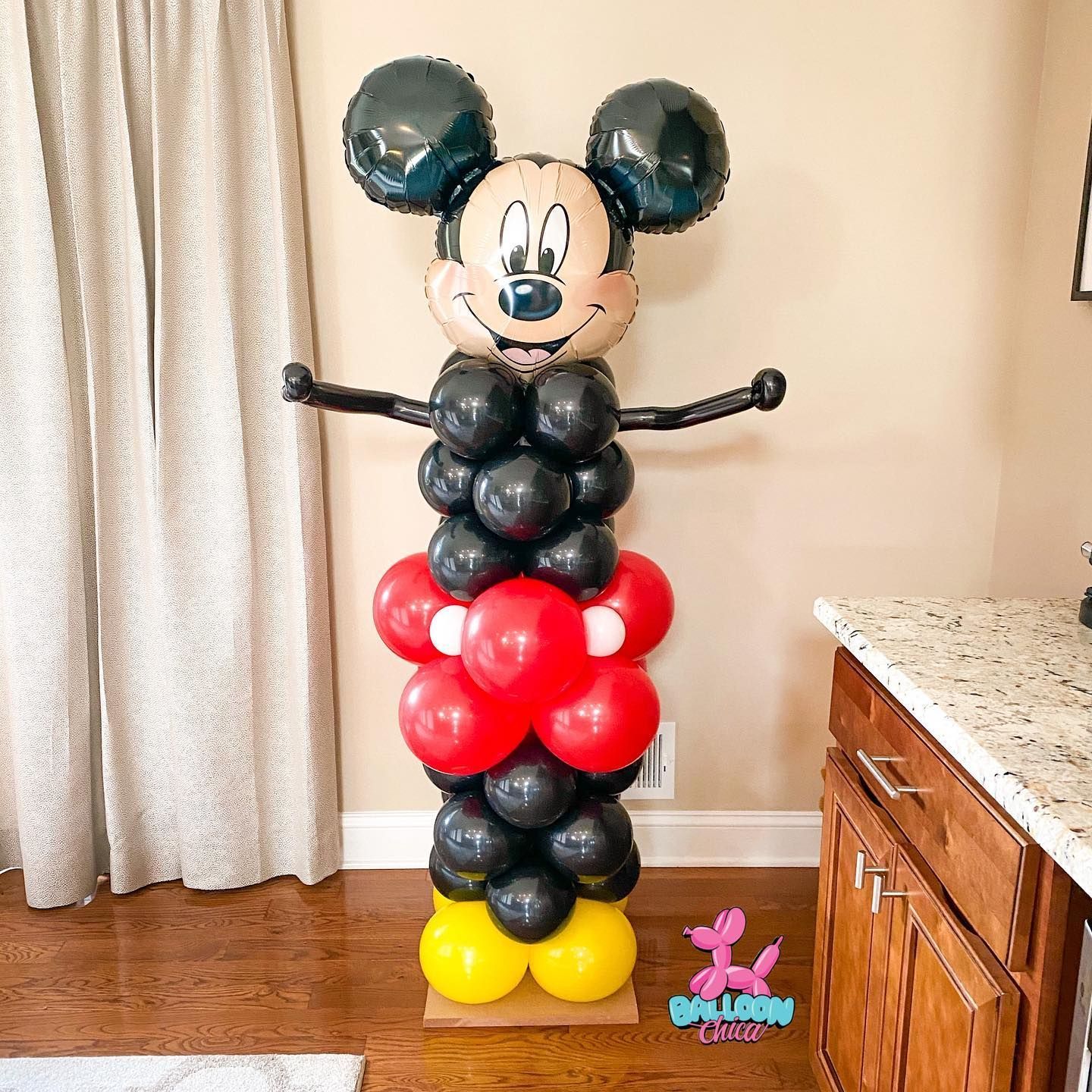 a mickey mouse balloon tower made of red , black and yellow balloons