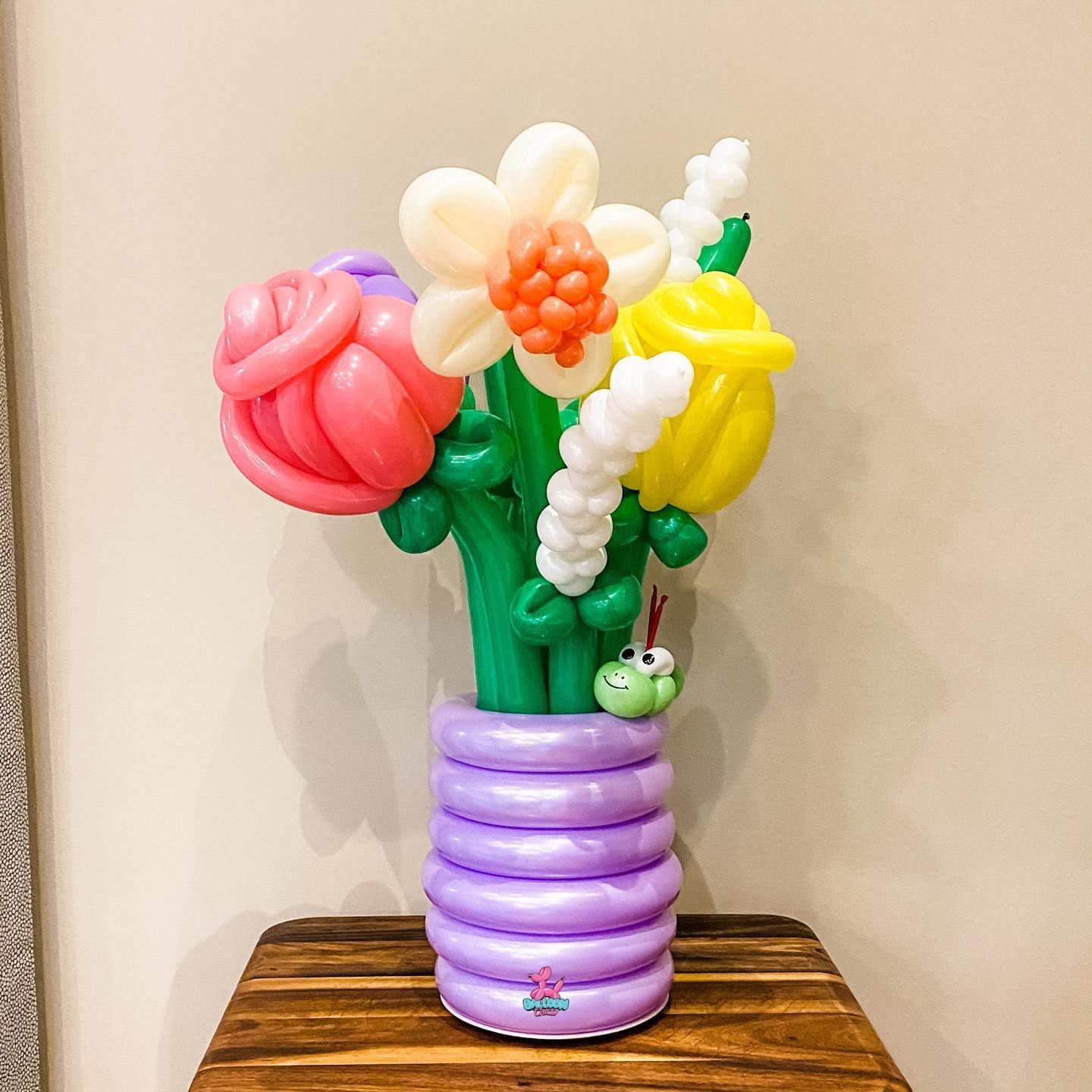 a vase filled with balloons shaped like flowers is sitting on a wooden table
