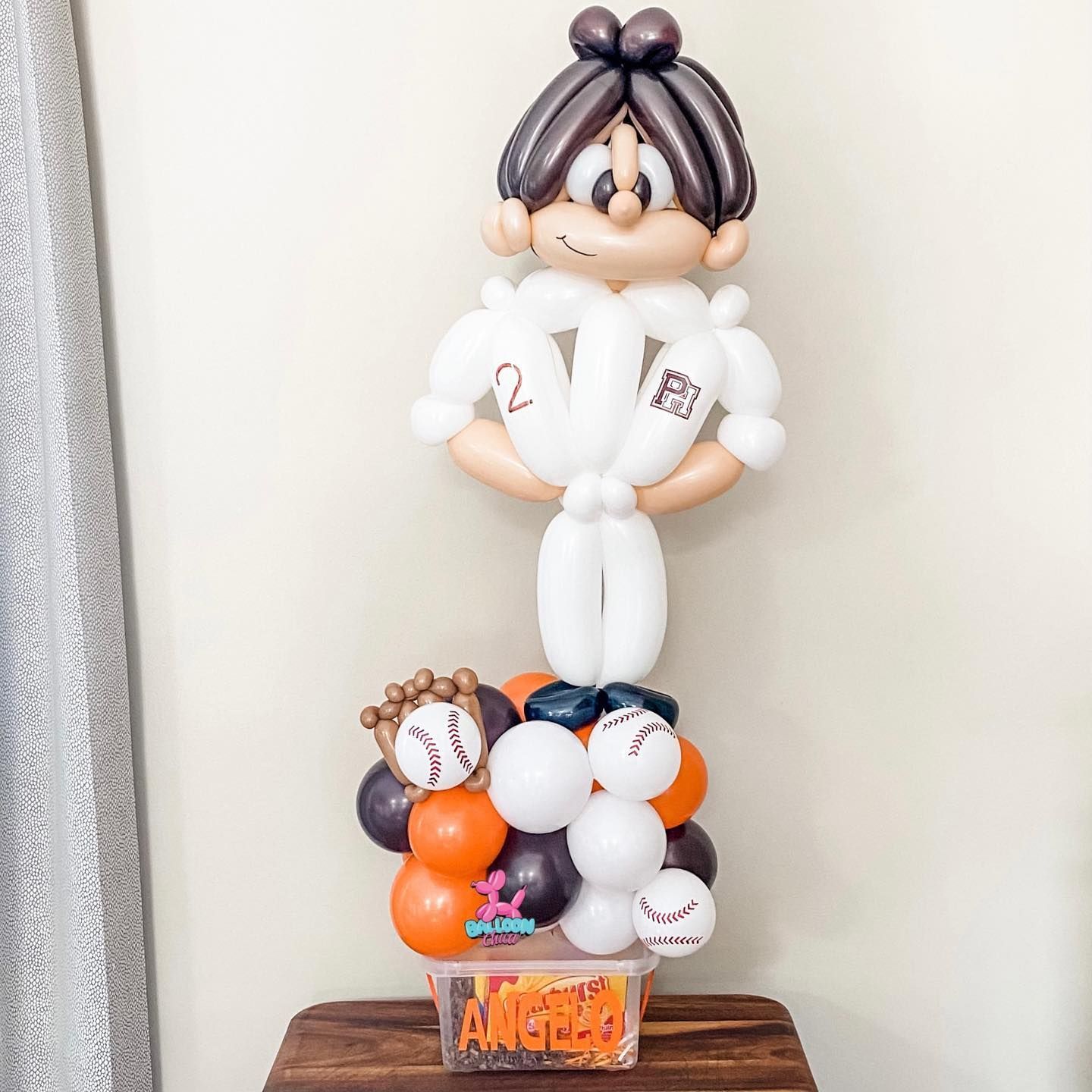a baseball player made out of balloons is standing on a table