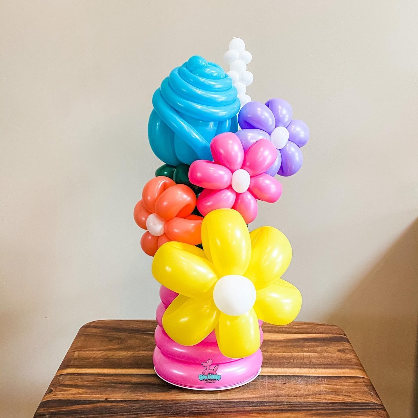 a bunch of balloons are stacked on top of each other on a wooden table