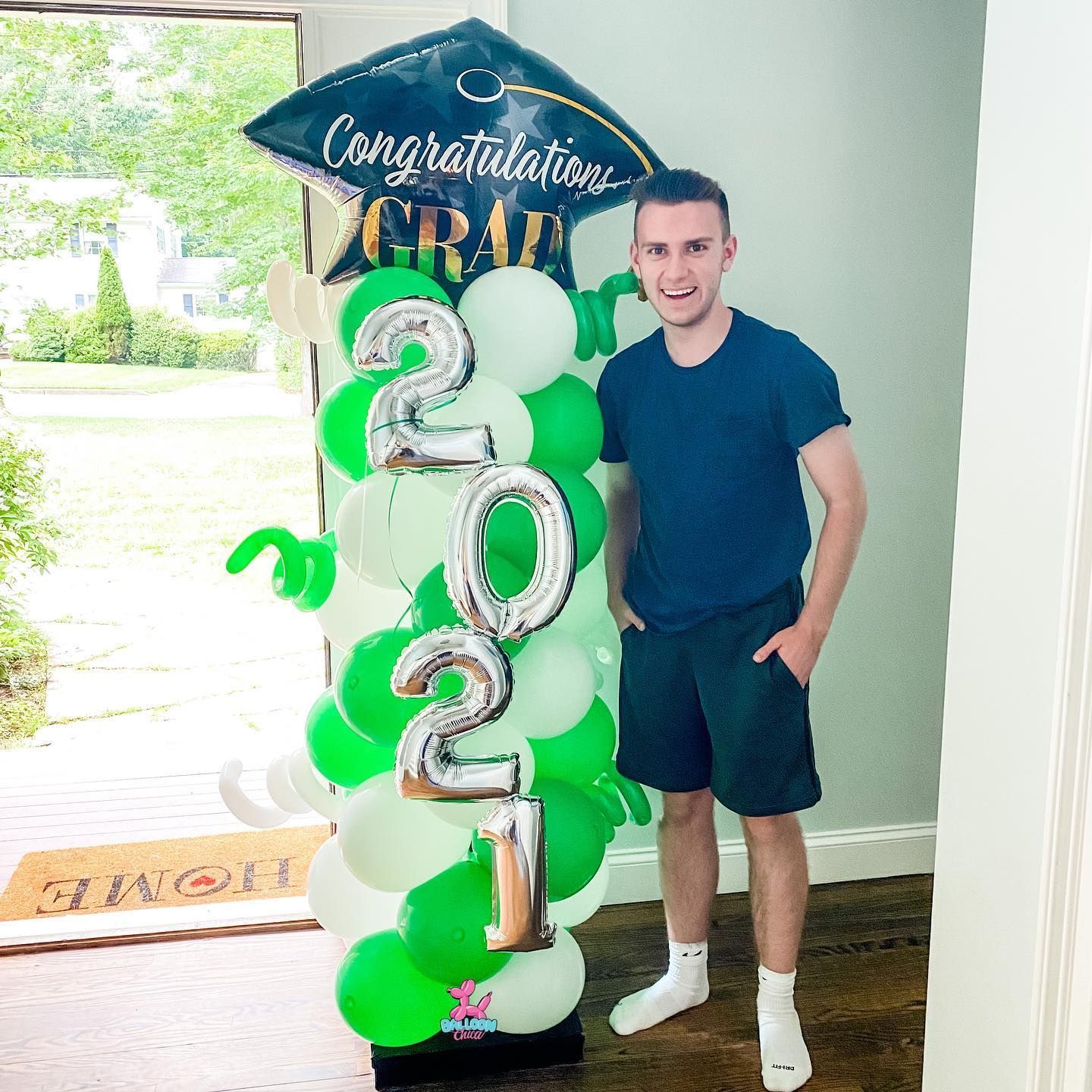 a man is standing in front of a graduation cap and balloons