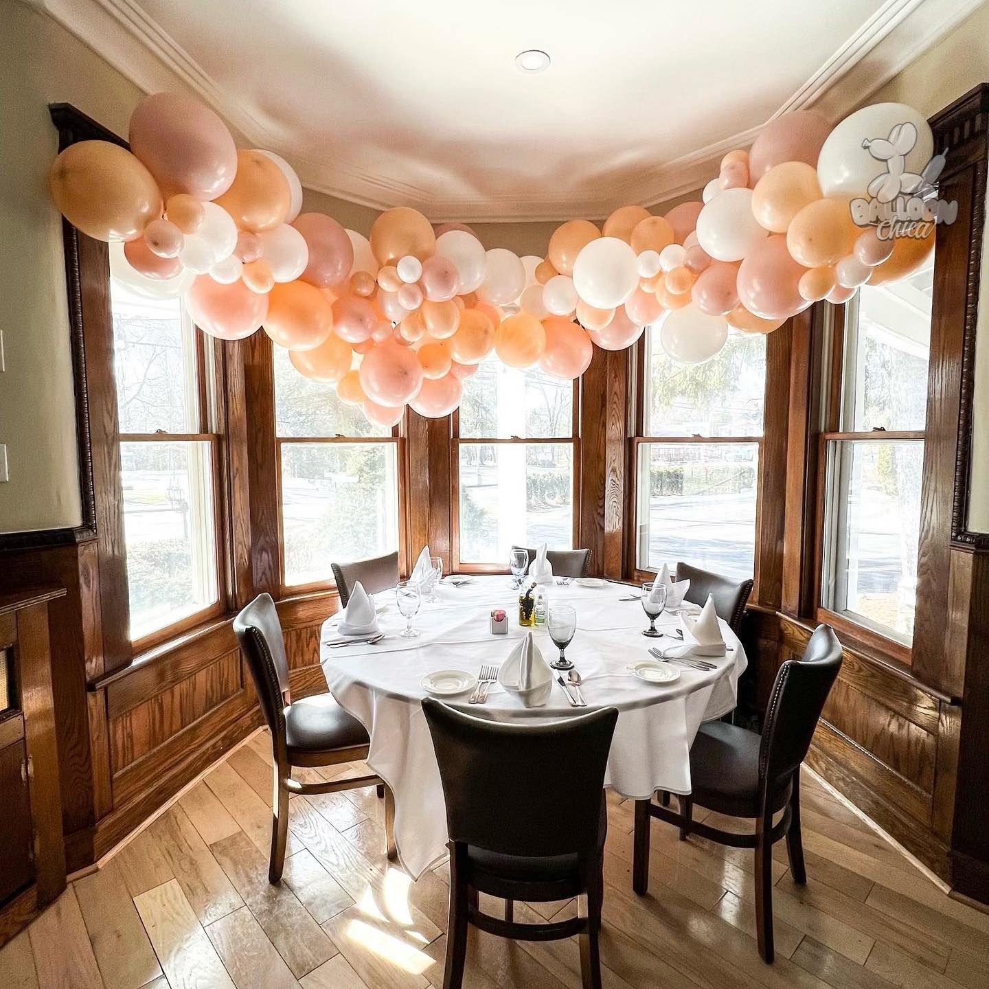 a room with a table and chairs and balloons hanging from the ceiling