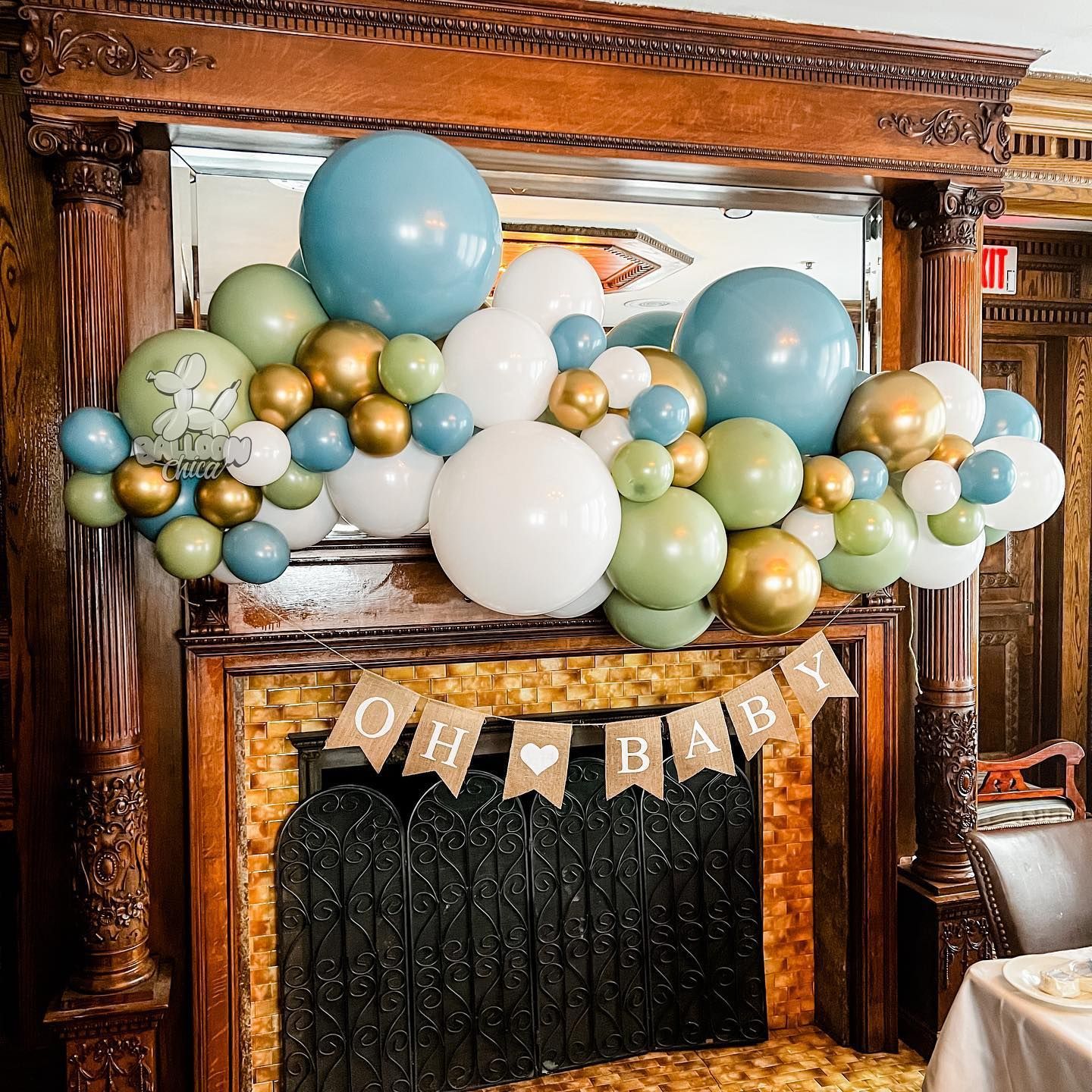 a fireplace decorated with balloons and a banner that says oh baby .