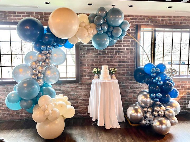 a room filled with balloons and a table with a cake on it