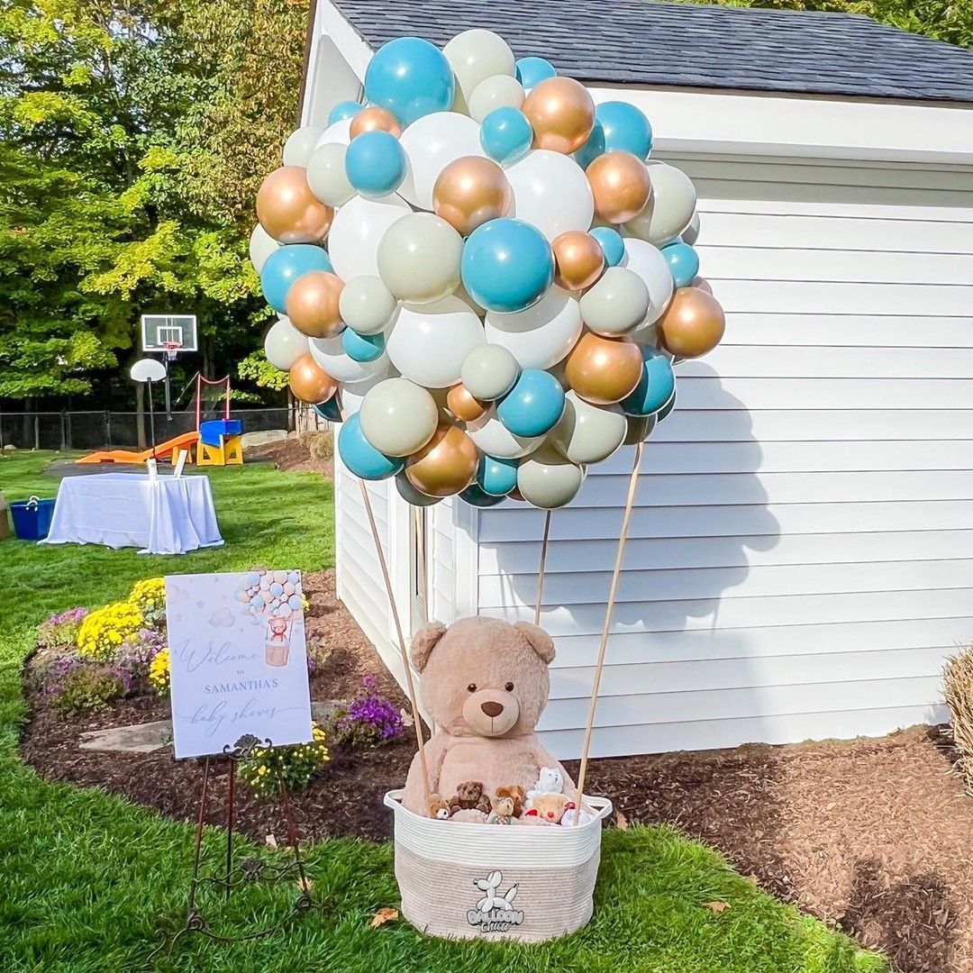 a teddy bear is sitting in a basket filled with balloons