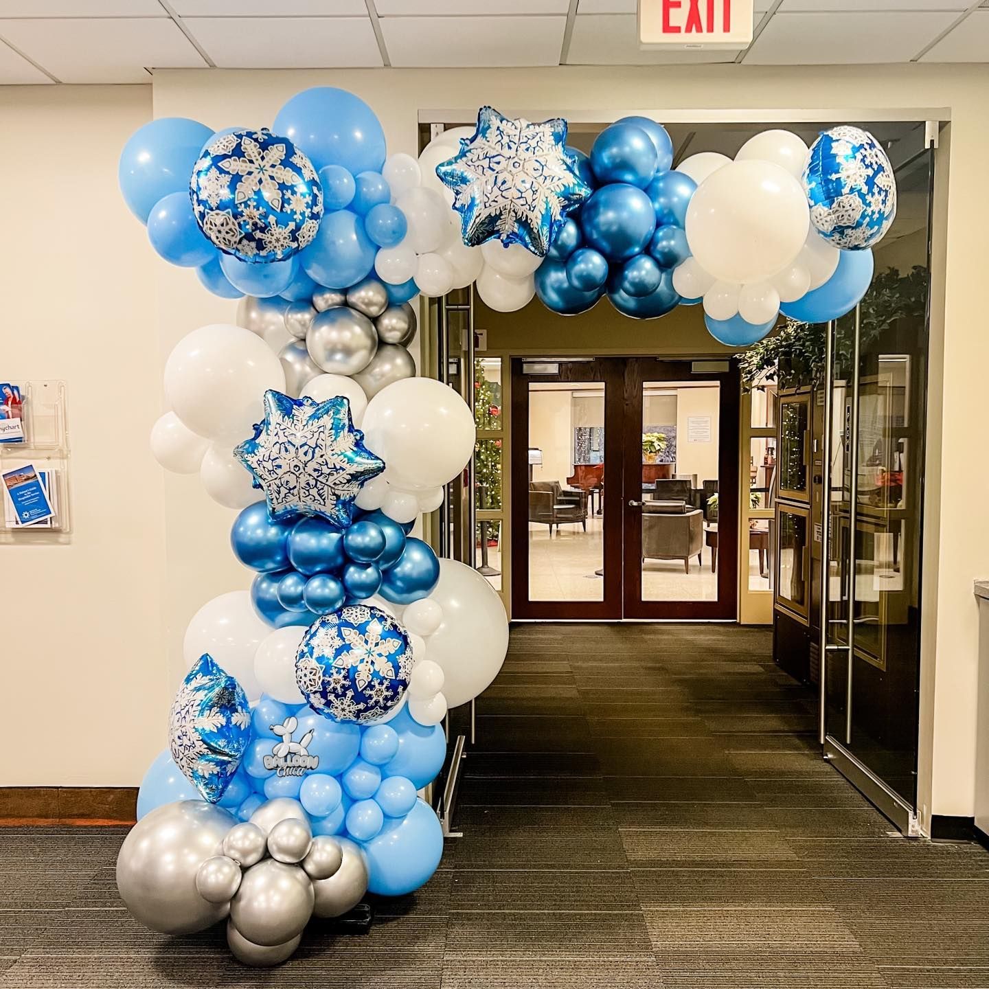 a bunch of blue and white balloons are sitting in a hallway