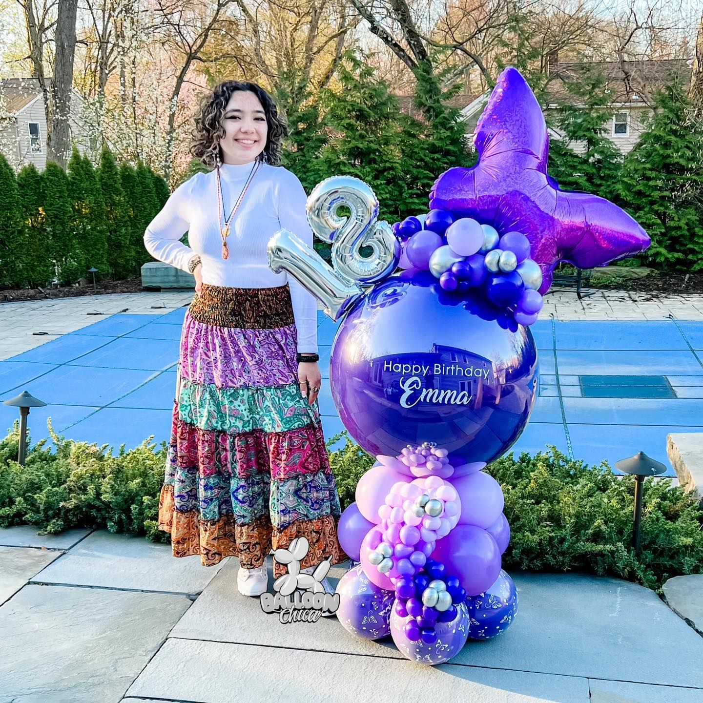 a woman is standing next to a purple balloon with the number 8 on it