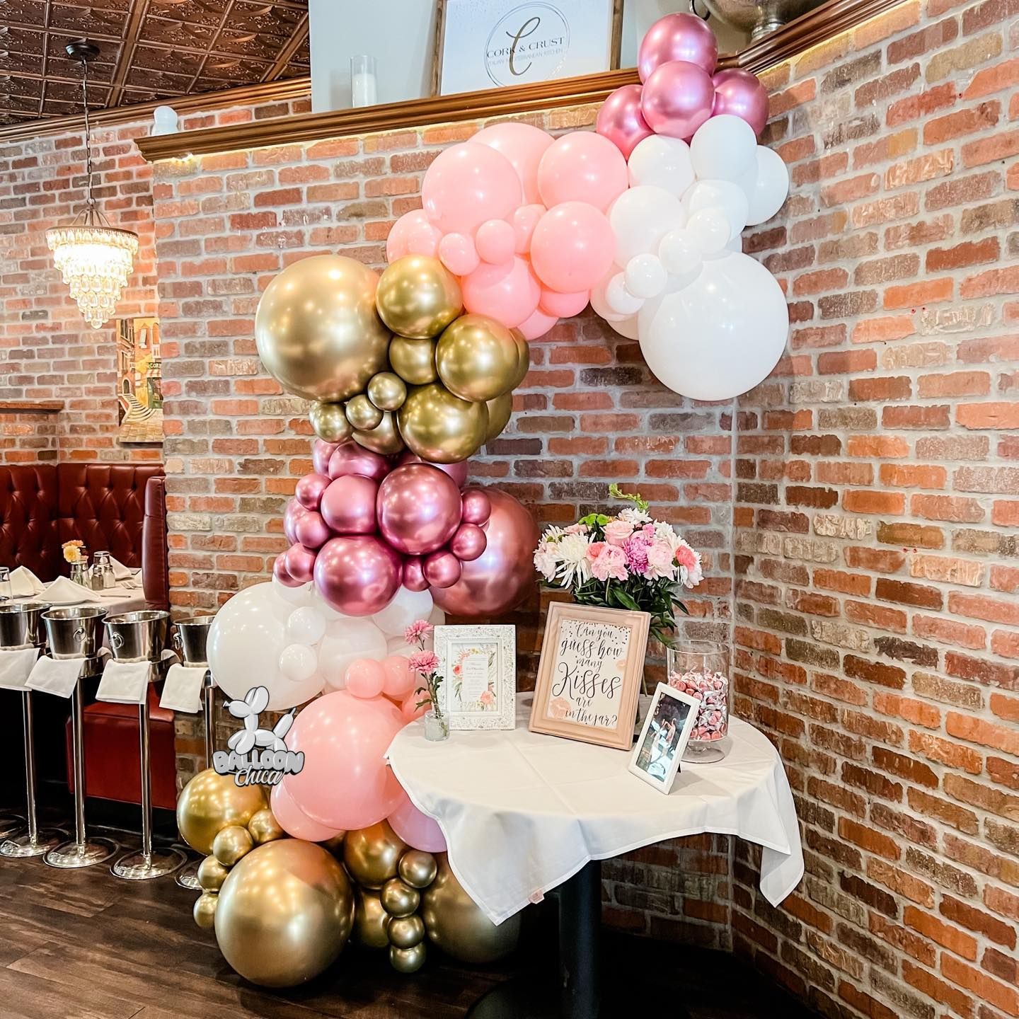 there is a table with balloons on it in front of a brick wall .