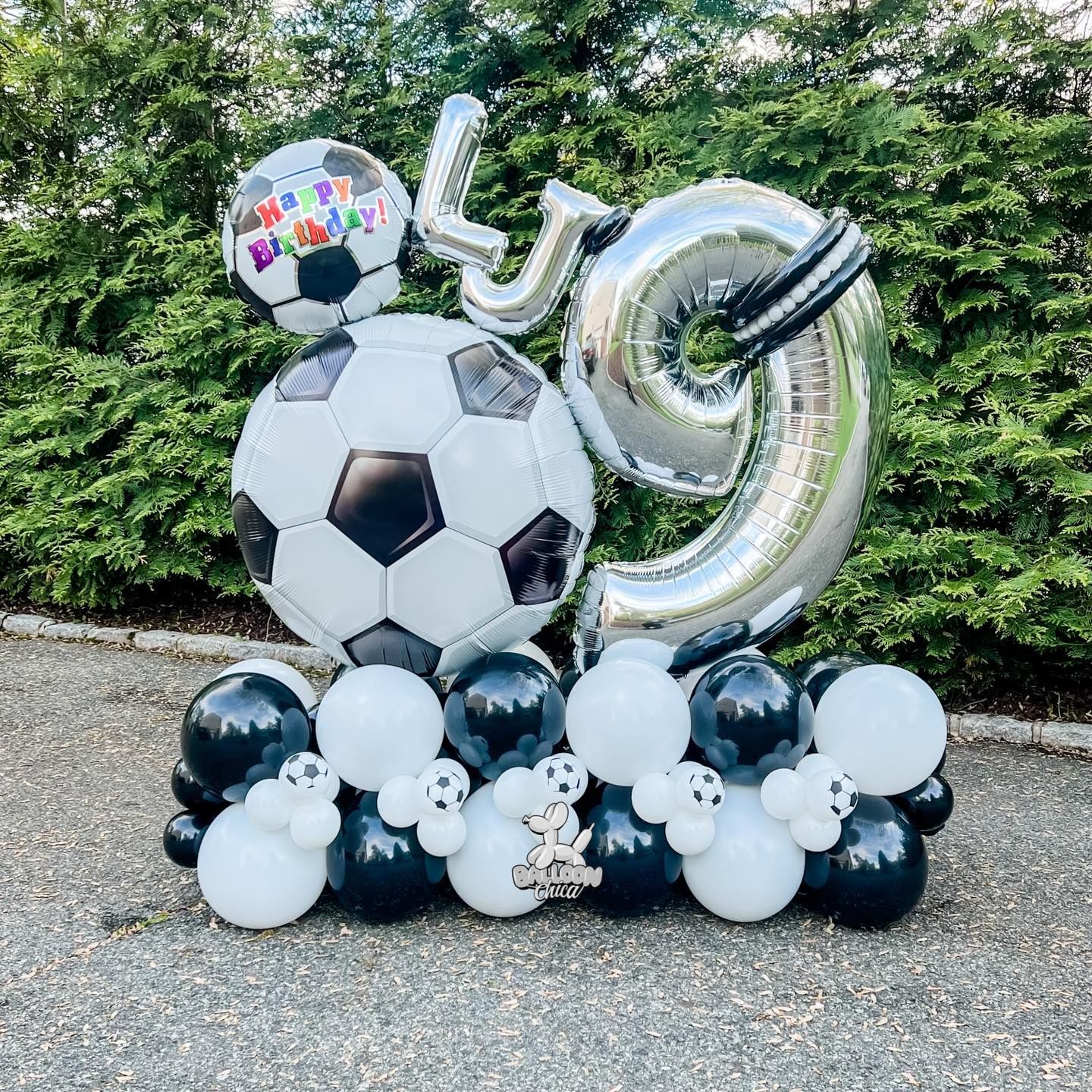 a bunch of black and white balloons with soccer balls and numbers on them