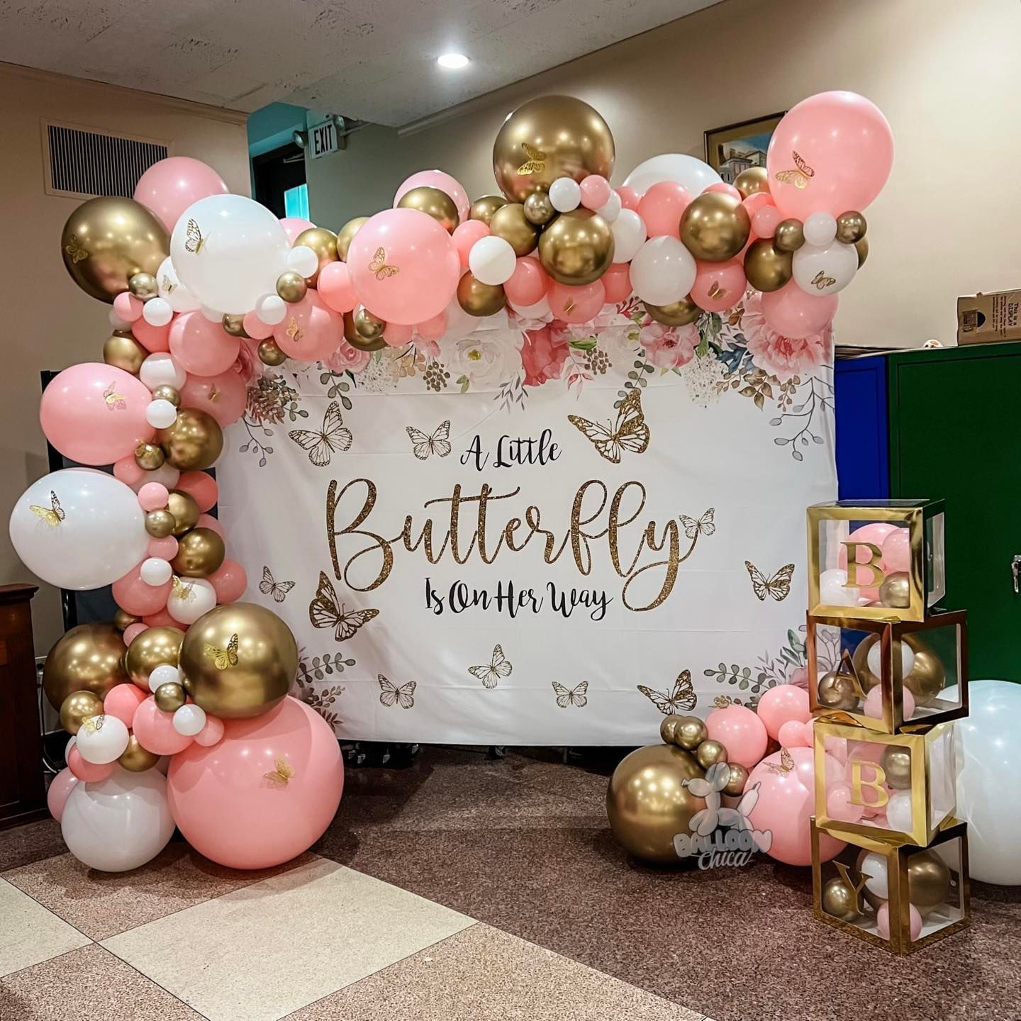 a room filled with pink and gold balloons and a sign that says a little butterfly on her way