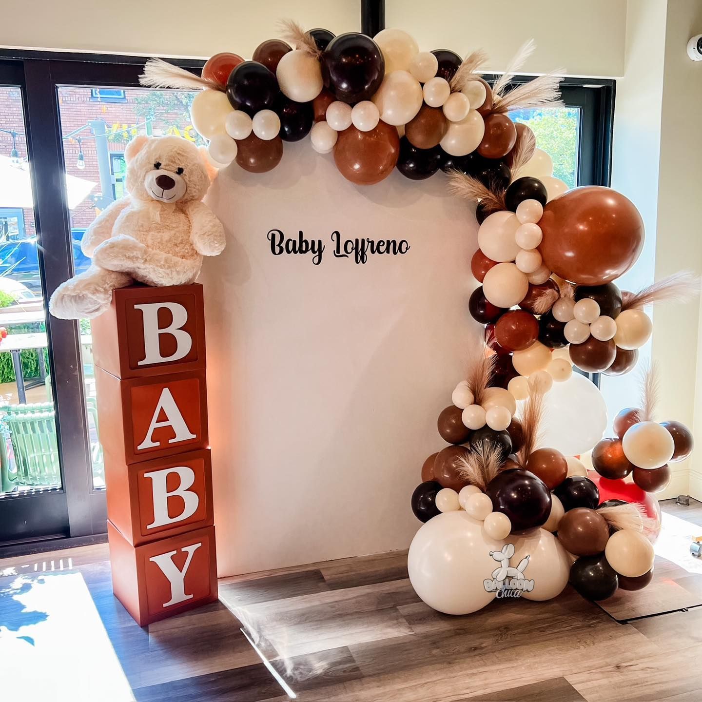 a baby shower decoration with balloons and a teddy bear