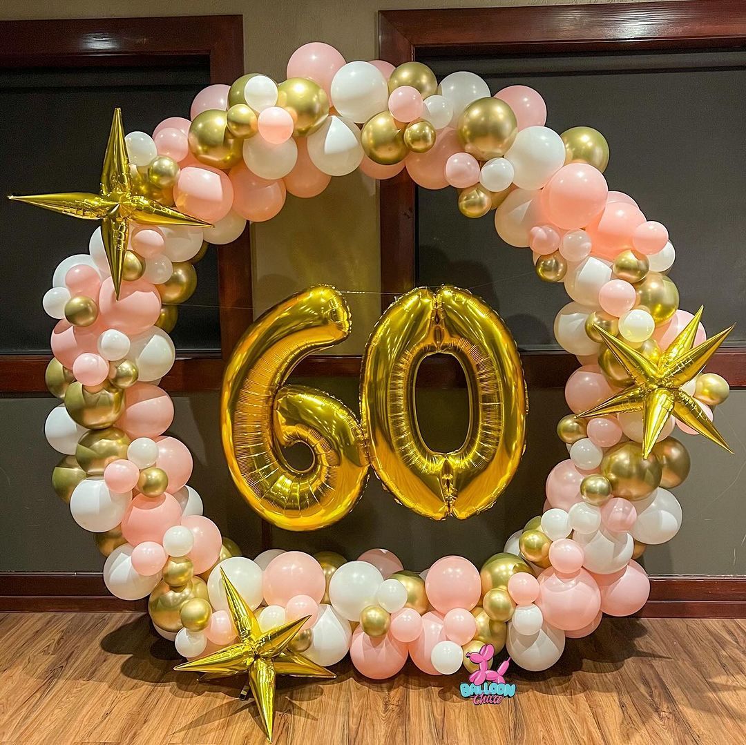 a wreath of pink and gold balloons with the number 60 in the middle