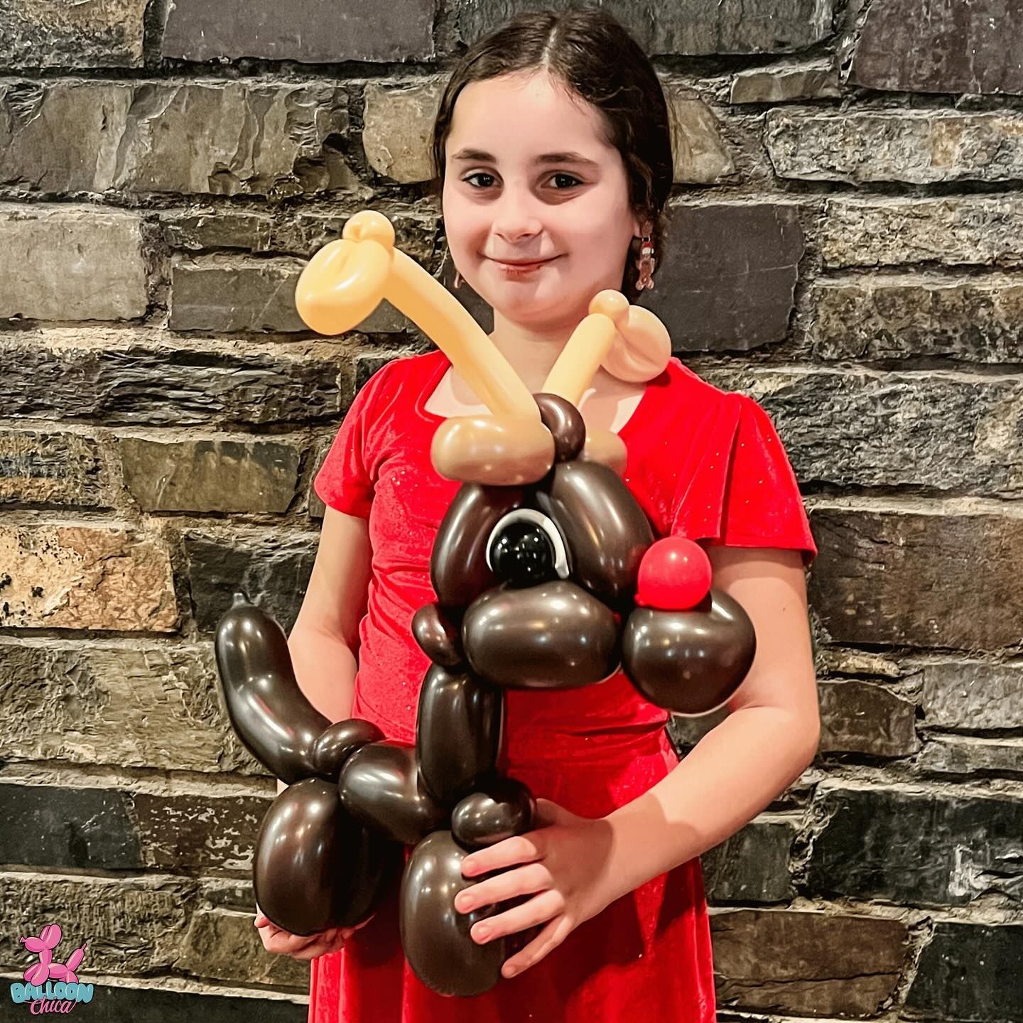 a little girl in a red dress is holding a balloon reindeer