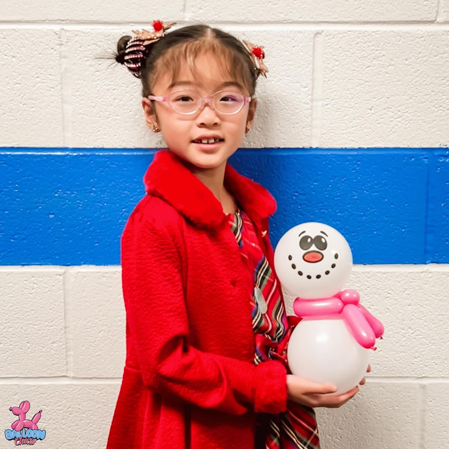 a little girl in a red coat is holding a balloon snowman