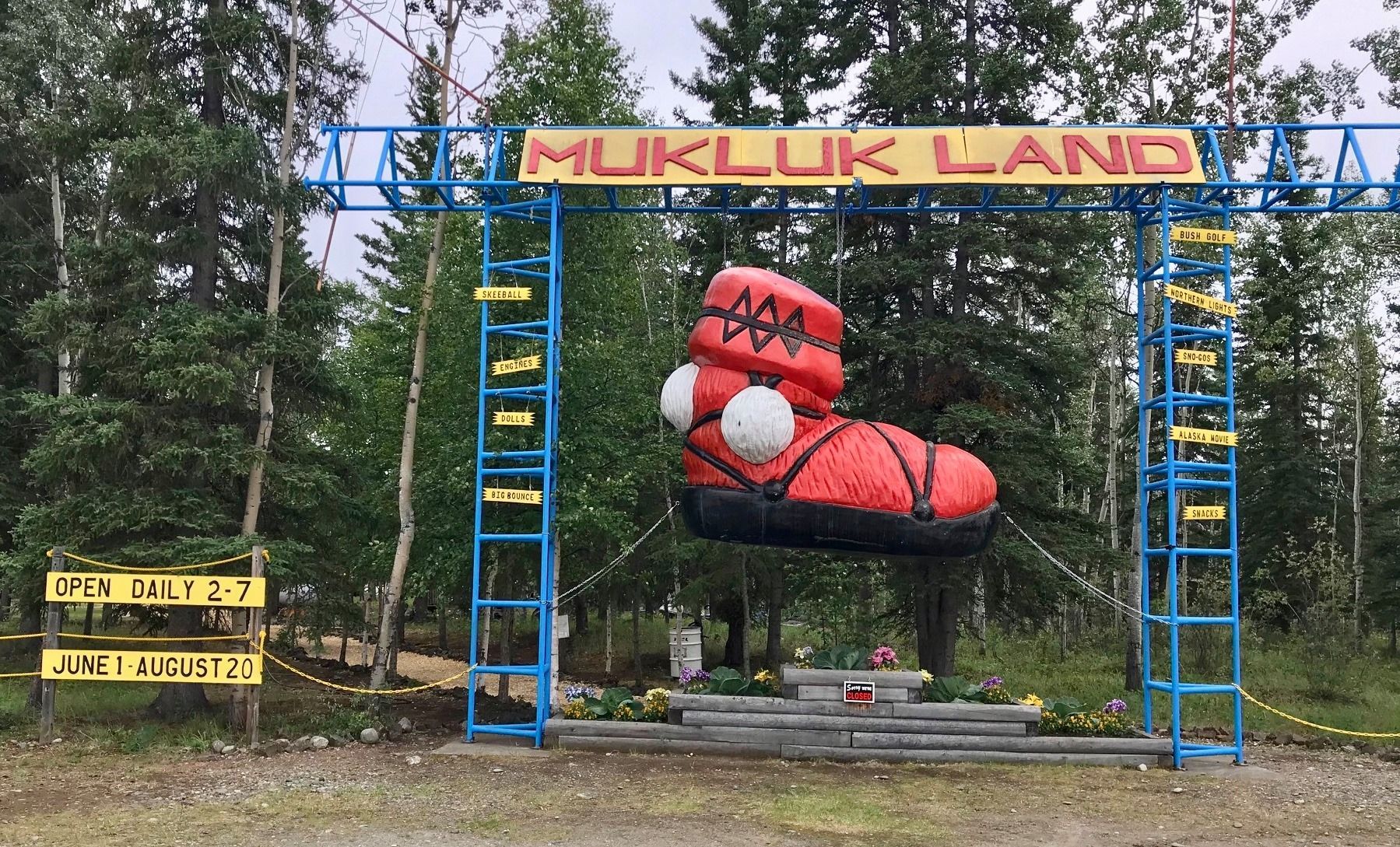 A large inflatable boot is hanging over a sign that says mukluk land