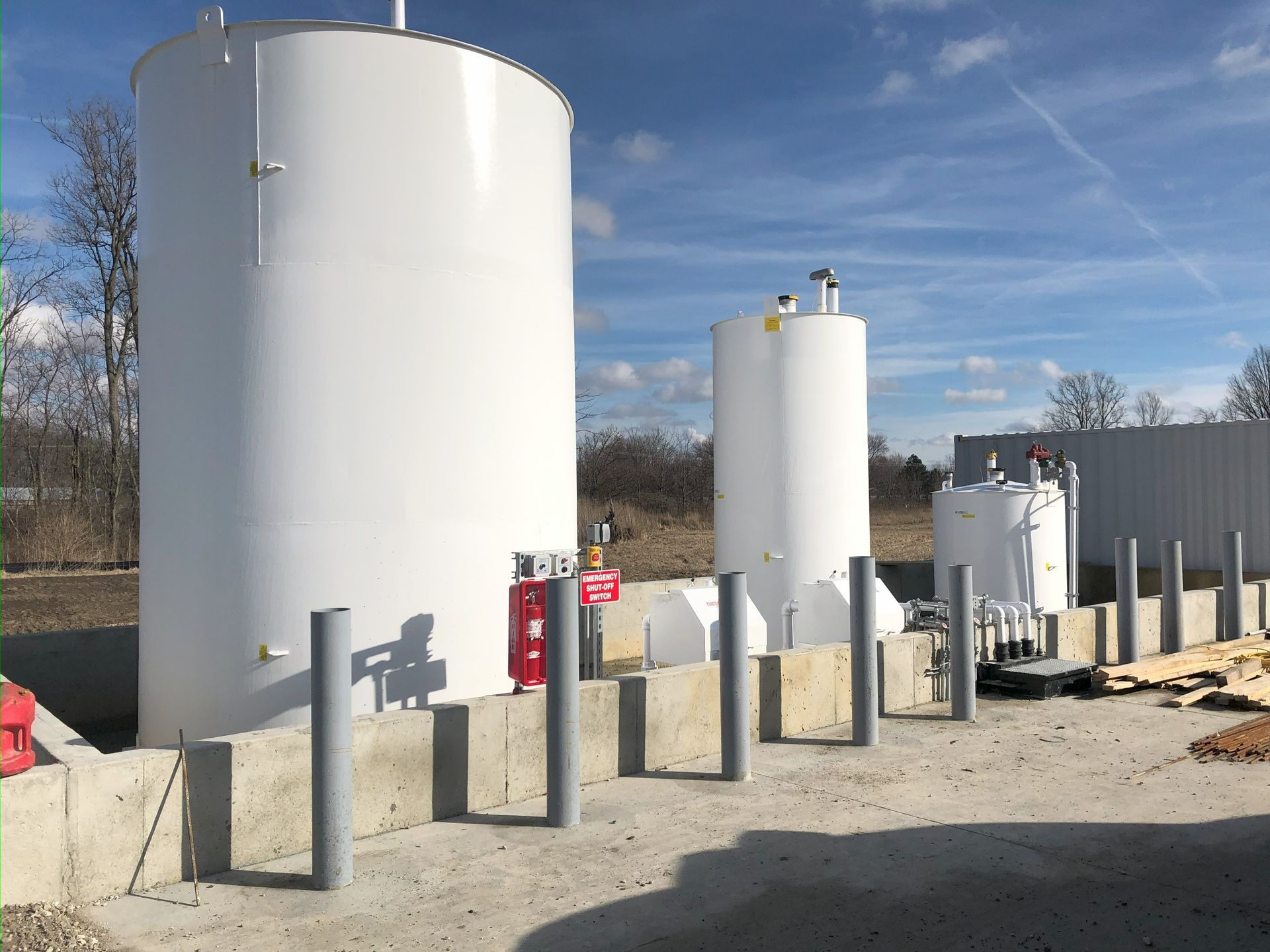 White industrial storage tanks outside, under a blue sky.