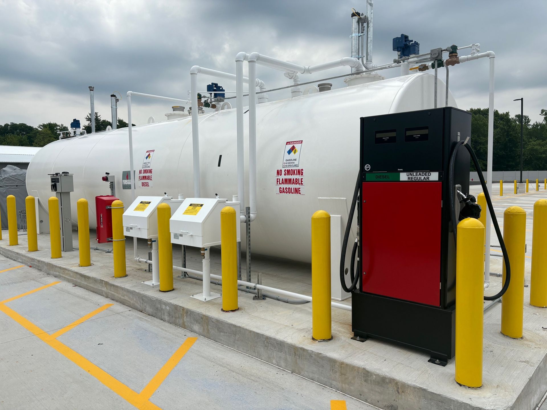 White propane tank with fuel pump, yellow bollards, outdoor setting.