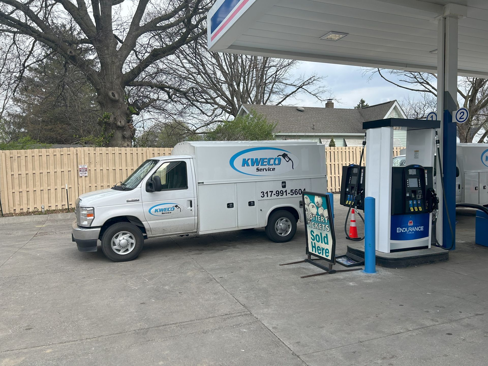 White service van at a gas pump with blue and white gas station.