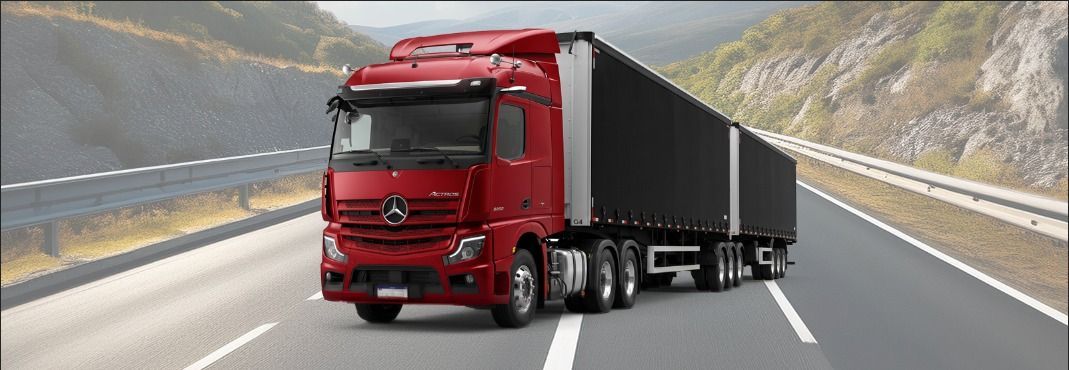 Red semi-truck hauling a black trailer driving on a mountain highway