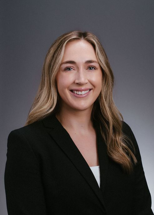 A woman in a black jacket is smiling for the camera.