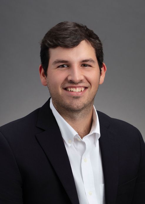 A man in a suit and white shirt is smiling for the camera.