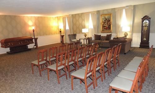 Quiet meeting room with rows of chairs, a long table, lamps, and wall art