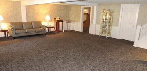 Empty carpeted living room with beige walls, sofa, lamps, and white doors