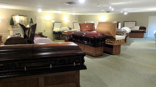 Coffins displayed in a funeral home showroom with upholstered caskets and soft lighting