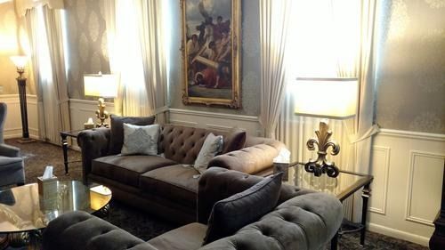 Elegant living room with tufted sofas, lamps, and a framed painting on the wall.