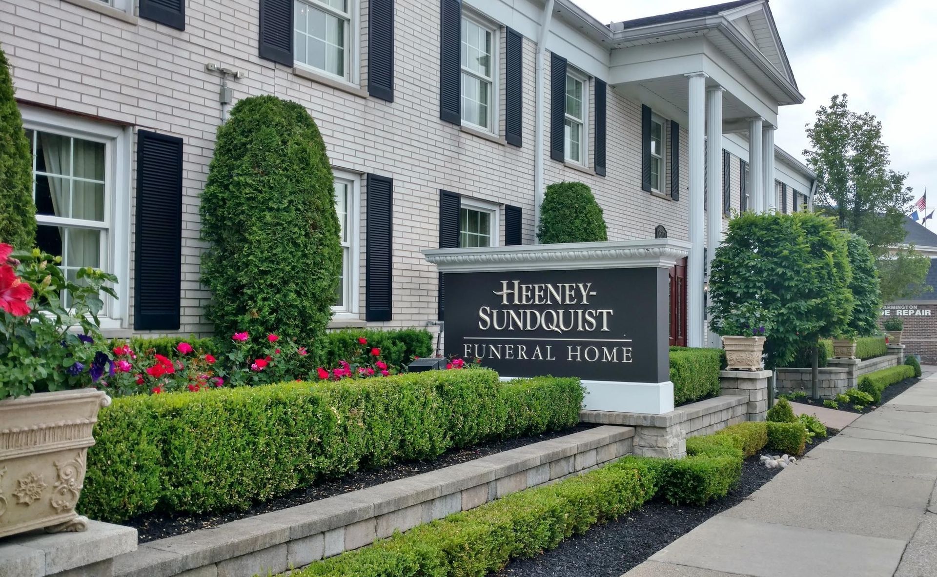 Sign at The Enclave at Sundiance Place beside a white building and landscaped sidewalk