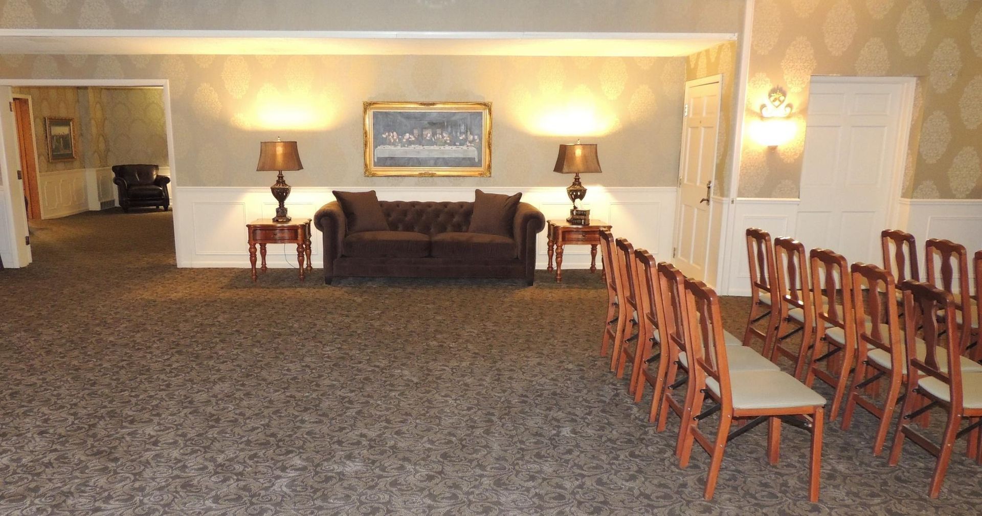 Banquet room with rows of chairs, a couch, lamps, and a carpeted floor