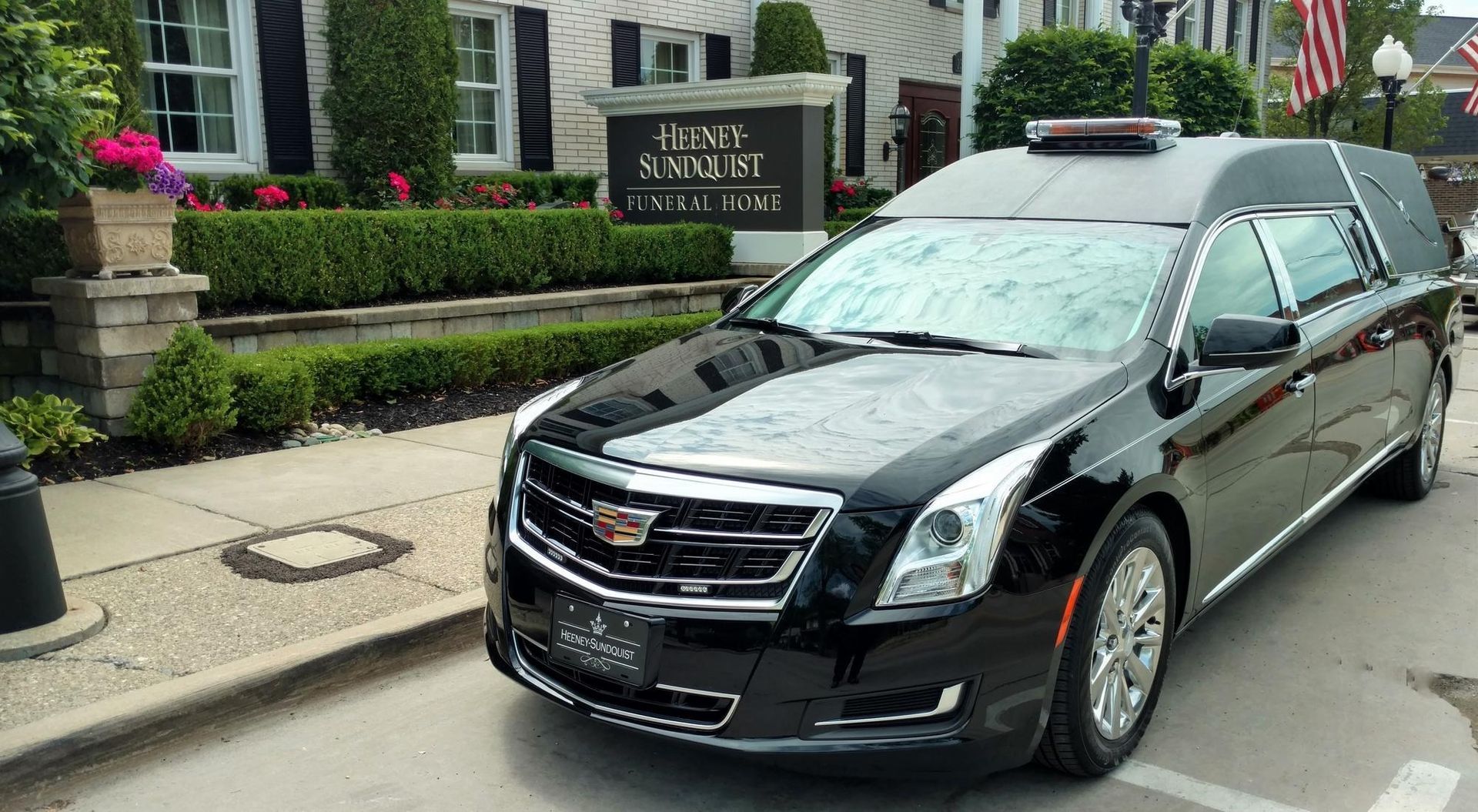Black Cadillac sedan parked on a city street in front of a hotel entrance
