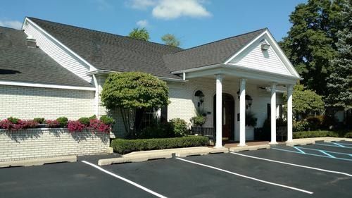 A white building with a covered entrance, columns, and empty parking spaces on a sunny day