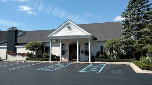 White clubhouse entrance with parking spaces and wheelchair-accessible markings in front