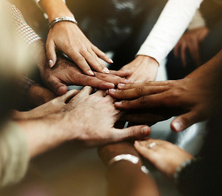 Hands stacked together in a circle, showing teamwork and unity.
