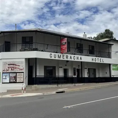 Cumeracha Hotel storefront on a quiet street, white facade with black trim and balcony