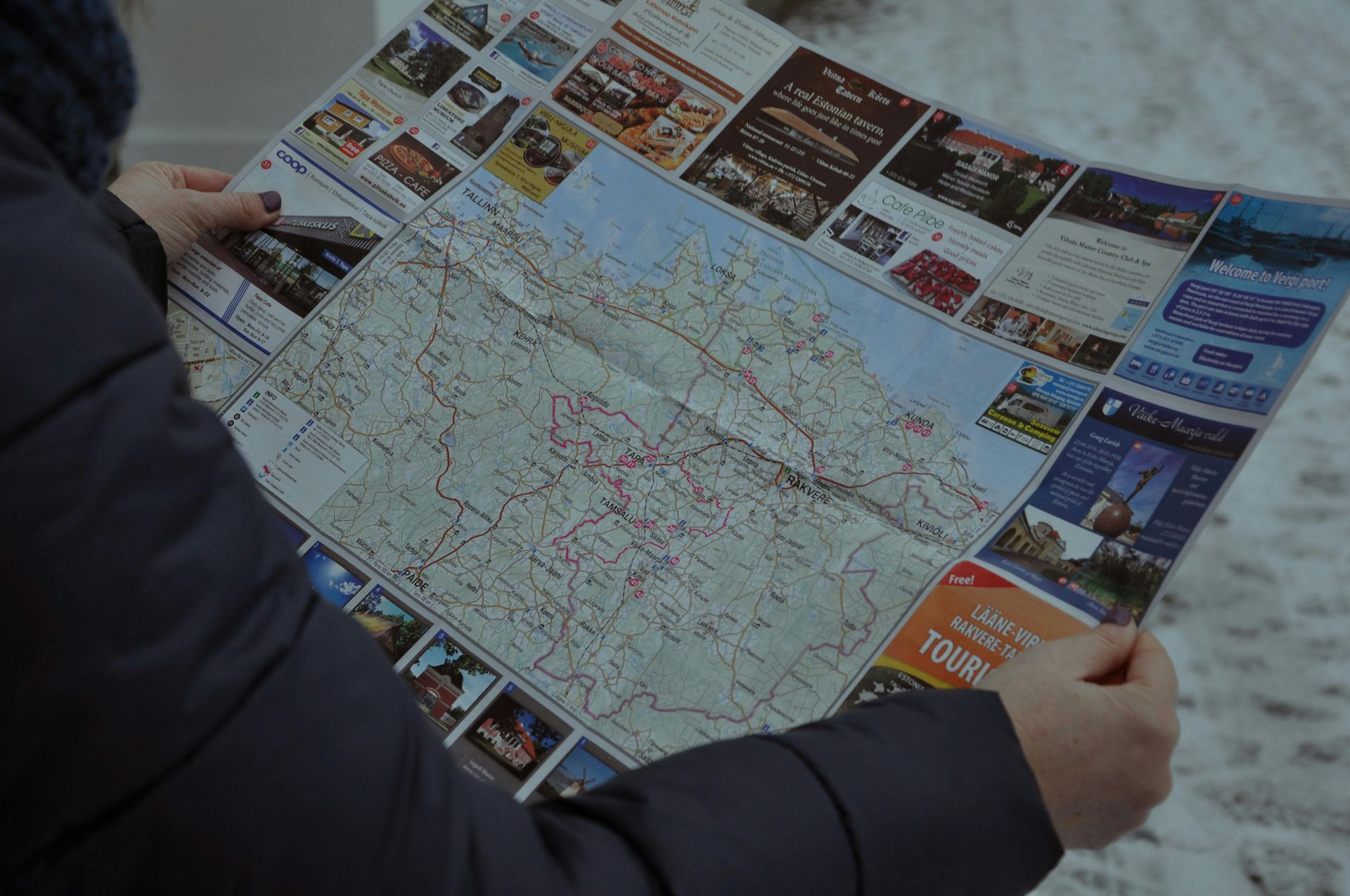 Person holding a large folded map outdoors in snowy conditions