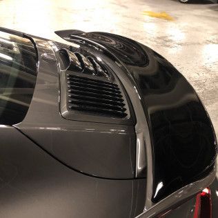 A close up of a car 's rear spoiler in a parking garage.