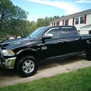 A black dodge ram truck is parked in front of a house.