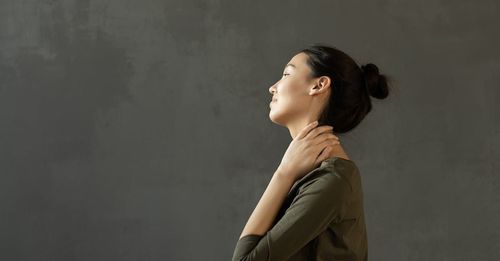 A woman is holding her neck in pain and looking up.