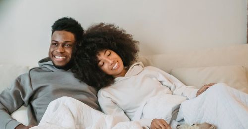 A smiling man and women sitting up in bed