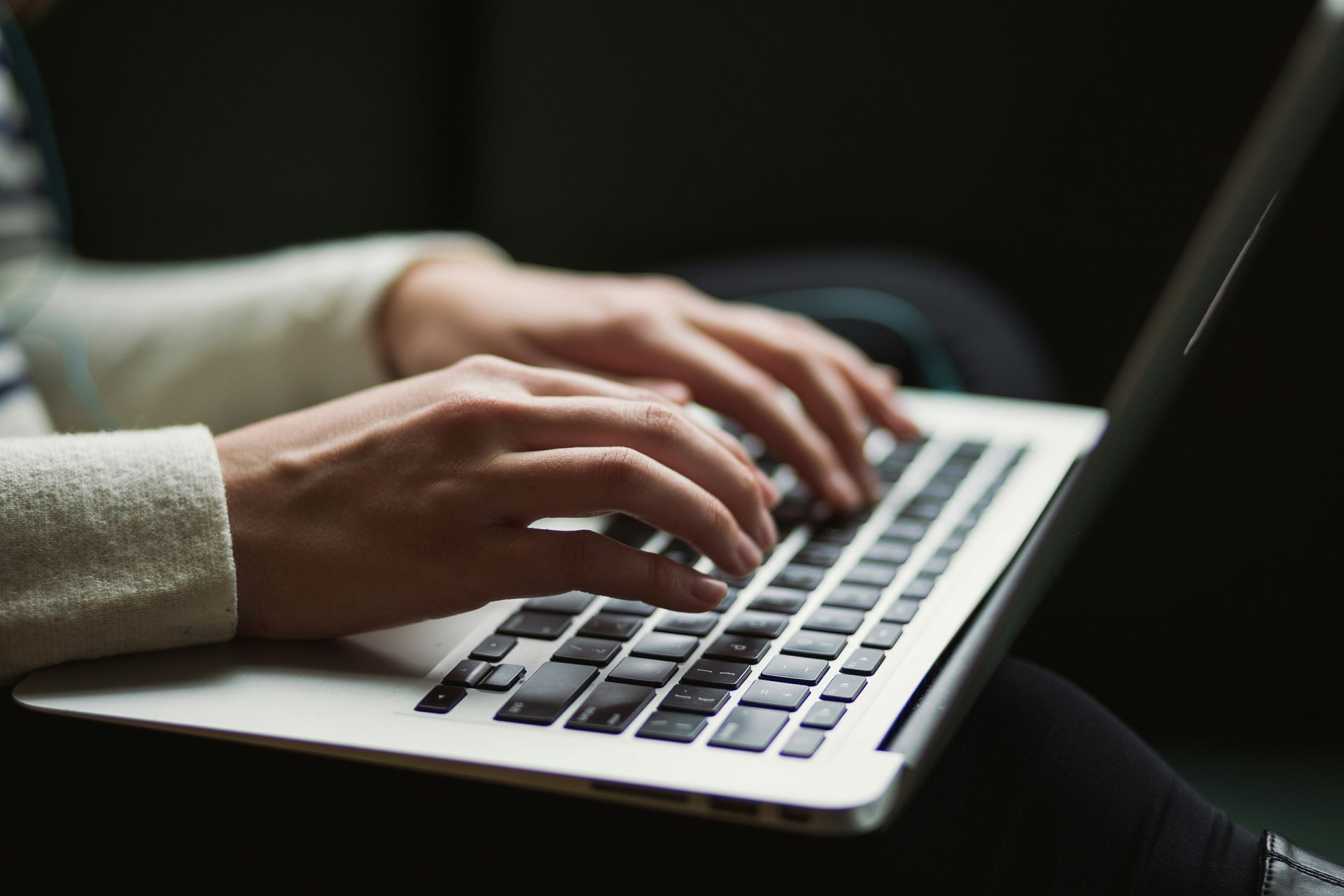 Person's hands typing on a silver laptop.