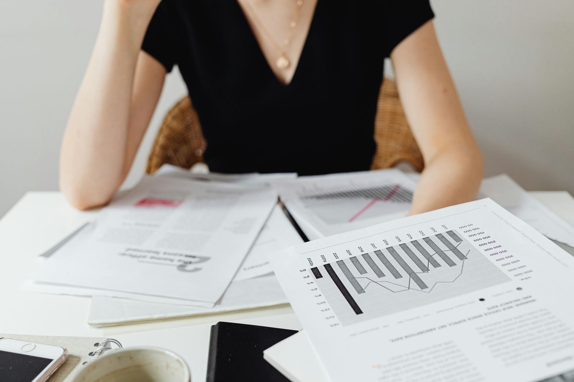 Woman reviewing financial documents with graphs and charts at a desk.