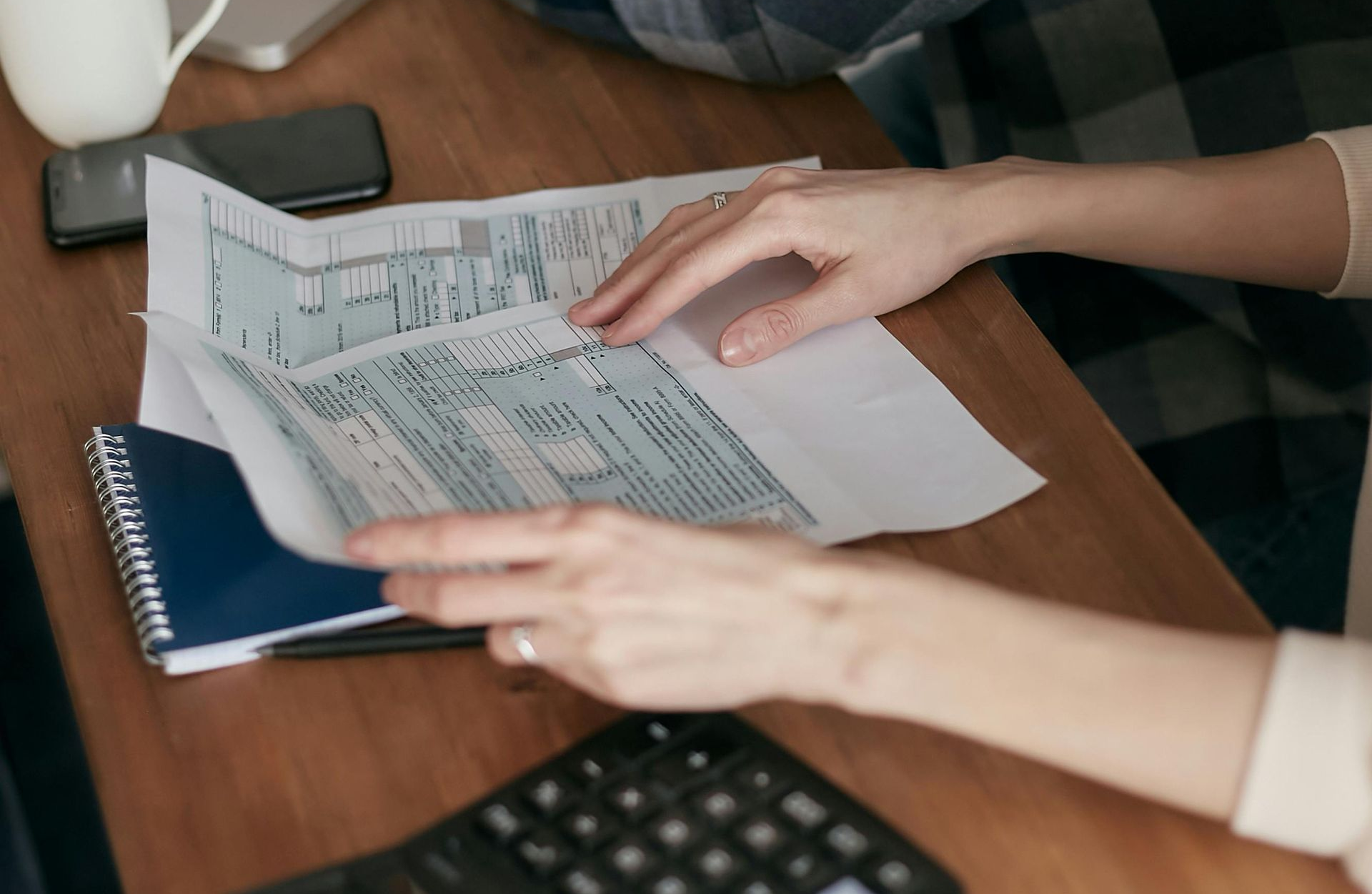 Notebook, glasses, calculator, and business plan on a wooden desk.