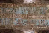 Ancient painted wall relief with blue and red scenes, figures, and hieroglyphic-like inscriptions