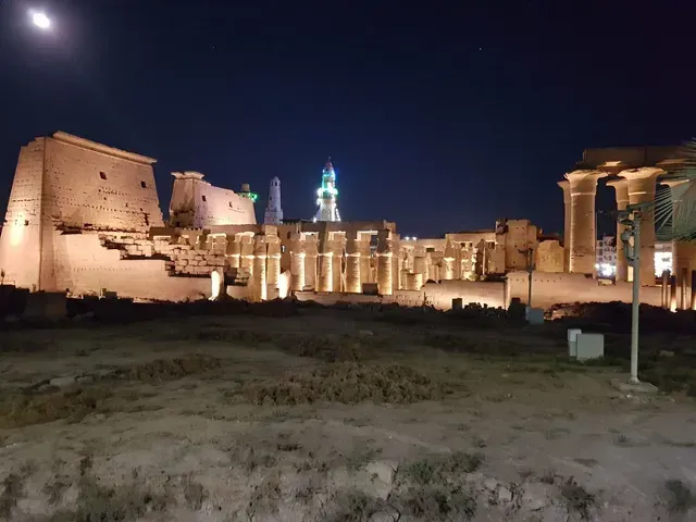 Illuminated ancient temple ruins at night with tall columns and a dark sky