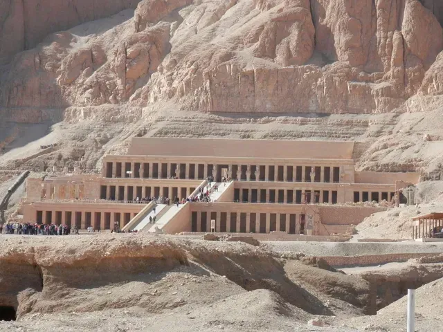 Desert hillside temple with terraces and columns built into reddish rock